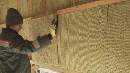 Man laying insulation in a wall