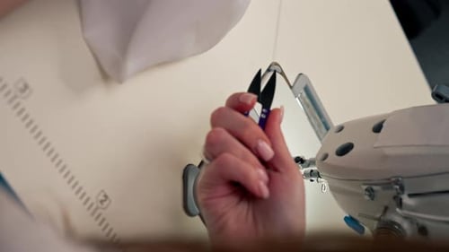 Vidéo verticale en gros plan dans l'atelier de couture Une jeune fille travaille avec une machine à coudre et du blanc