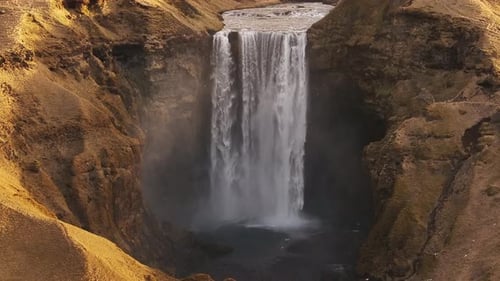 Skógafoss Iceland waterfall drone view - epic fall, mist and rugged golden cliffs from above