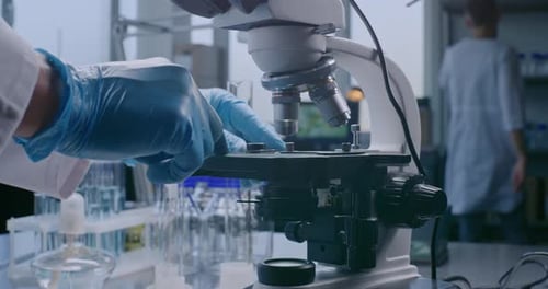 Close Up of Professional Scientist Putting Slide with Test Sample Under Microscope