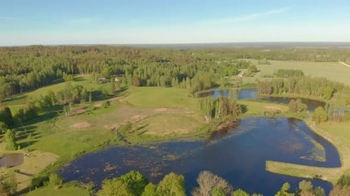Slow flying drone aerial over lakes at the edge of a forest in Latvia's Kurzeme
