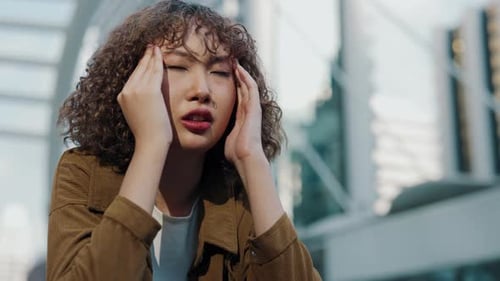 Woman Massaging Temples Suffering from Headache in City