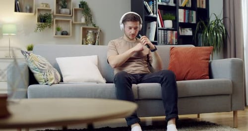 Man Listening to Music on Headphones on Sofa