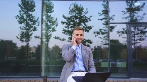 Young Adult Working on Laptop and Talking on Phone