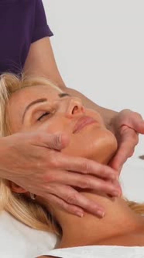 Woman receiving facial massage in spa, close-up