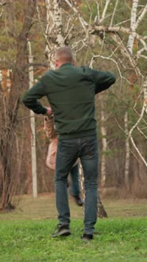 Vater und Tochter spielen im Park Man wirls kleines Mädchen in rosa Jacke auf grünem Feld