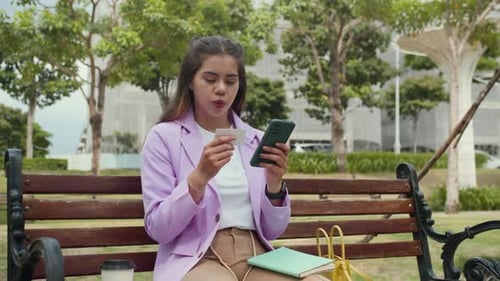 Multicultural Girl Using Smartphone while Paying by Credit Card in Park