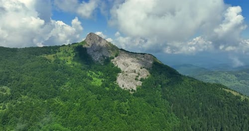 Flight over green mountain peaks. A beautiful sunny summer day at high altitude with thick clouds an
