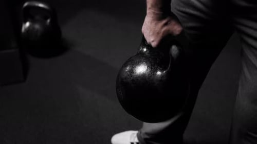 O braço inflado de um homem levanta um peso pesado praticando esportes na academia