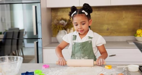 Happy girl kids baking cookies with rolling pin in kitchen, house and home for childhood fun