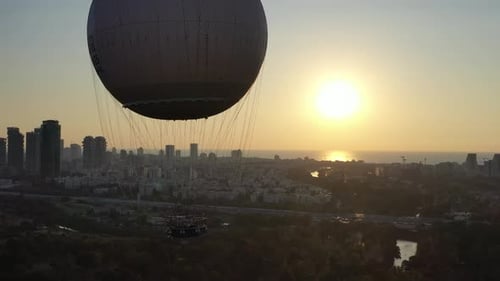 Aerial Shot Of Hot Air Balloon Descending Over Yarkon Park Against Sky In City