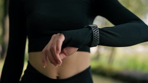 Close-up of a girl looking at the sports watch on her hand to determine number of kilometers she run