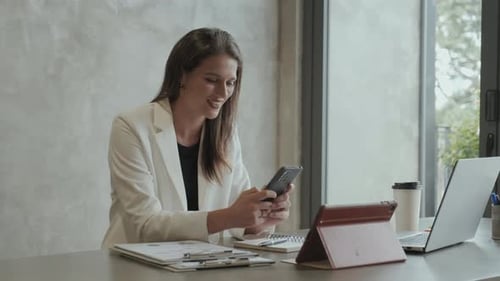 Woman Using Phone While Sitting at Desk