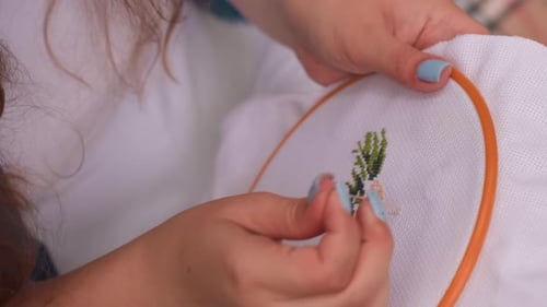 Close Up Of Fashion Designer With Painted Nails Embroidering Fabric Carefully