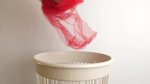 03, A piece of red fabric is recycled and thrown into the trash. The concept of disposal and recycli