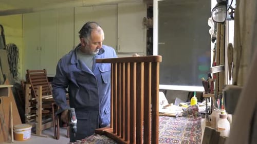 A Carpenter in His Workshop Assembles a Handmade Chair Screws a Screw Confirms It with a Screwdriver