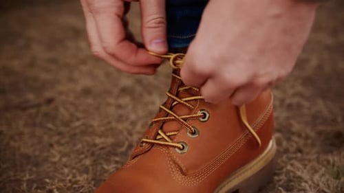 Man Tying the Laces on Brown Leather Boots