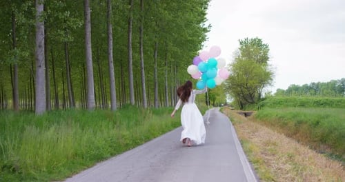 Woman Running with Balloons on Rural Road