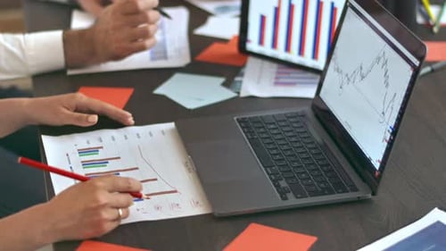 Three people are working and talking in the office. Gadgets and papers with graphs and information