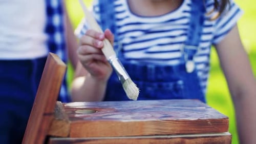 Père et fille profitant d'une journée d'été ensoleillée en peignant ensemble un nichoir en bois