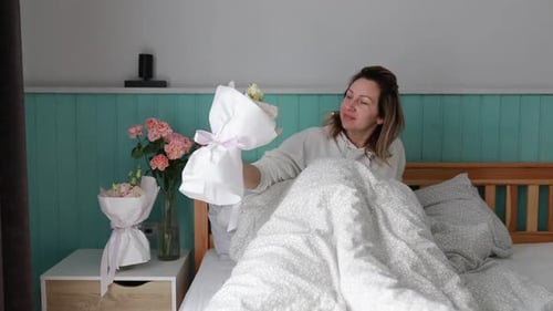 Frauen wachen auf und sitzen im Bett neben einer Blumenvase