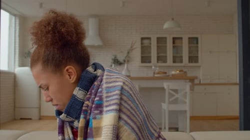 Woman Coughing and Rubbing Sore Throat Indoors