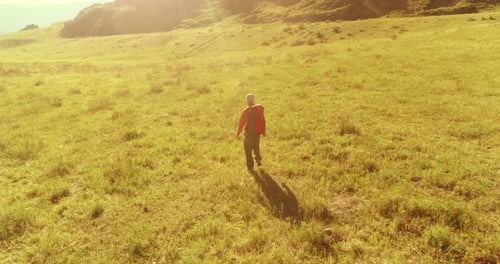 Flight Over Backpack Hiking Tourist Walking Across Green Mountain Field Huge Rural Valley at Summer