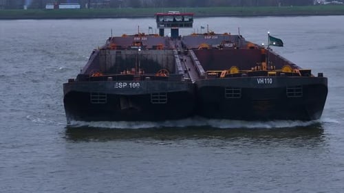 Goods barge sailing across Oude Maas river, vessel deck vacant for cargo