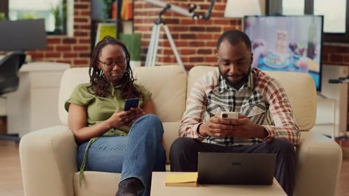 Relaxed Couple Using Cellphones Together on Sofa
