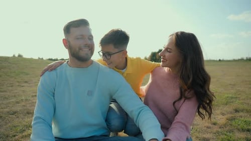 Happy Family Embrace Outdoors in Grassy Field
