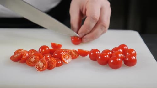 Couteau à mains masculines tenant un couteau coupant des tomates cerises pour salade ou plat