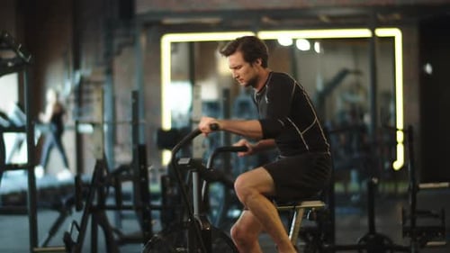 Eager male athlete training on exercycle at gym cardio workout in slow motion