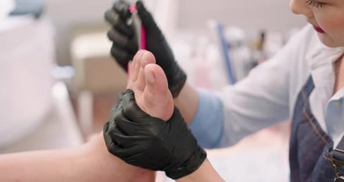 closeup view of asian adult female technician filing senior customer foot using tool with both hands