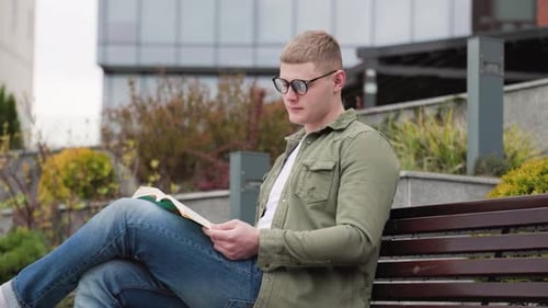 Männlicher Bücherwurm genießt die Natur beim Lesen Junger Mann liest im Freien