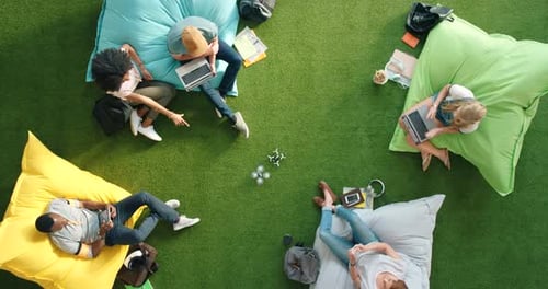 Diverse group of modern technology students using fun outdoor lounge to boost startup creativity