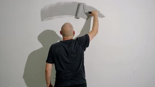 Man Painting Wall with Gray Paint Roller