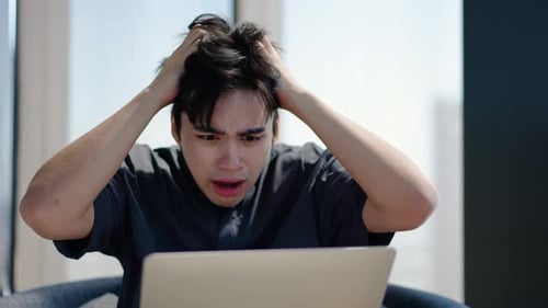 Young Adult Surprised by Laptop News Indoors