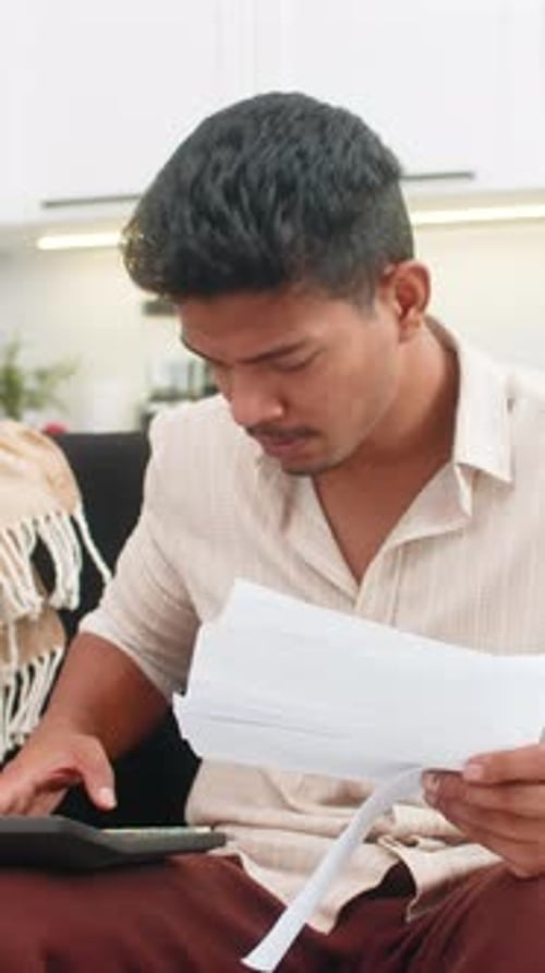 Man Looks Worried While Calculating Finances at Home