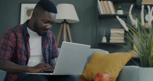 Man Sitting on Couch Working on Laptop