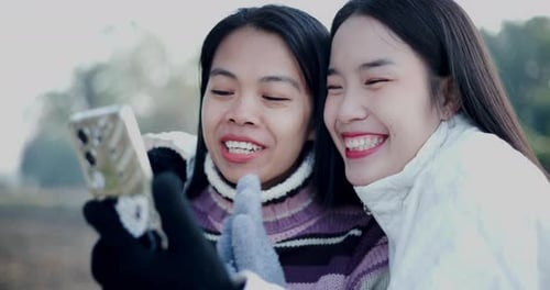 Smiling Women Using Smartphone Together Outdoors