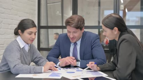 Three Colleagues Collaborating on Data Analysis in Office