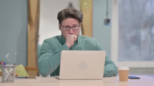 Man Coughing While Sitting at his Laptop