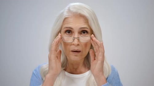 Senior Woman Adjusting Glasses with Surprised Expression