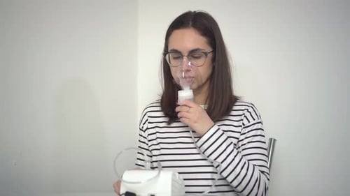 Une jeune femme respire à travers un masque inhalateur Une fille à lunettes avec un masque à oxygène est en train d'être