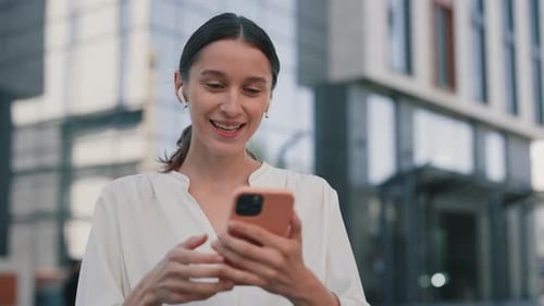 Cheerful Beautiful Woman Chatting on Video Call Using Wireless Earphones at Street Close Up
