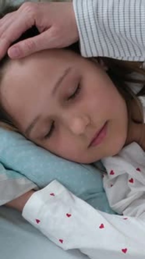 La madre controla la temperatura del niño tocando la frente mientras la niña descansa en la cama Concepto de fiebre