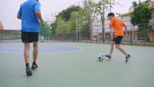 Asian two sportsman practicing football playing in the outdoors stadium.