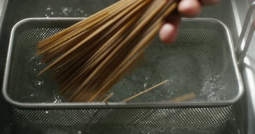 Italian genuine pasta is put to boil in a professional basket to boil and cook