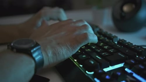 Primer plano de manos masculinas escribiendo en un clip de teclado brillante El hombre está escribiendo en un teclado retroiluminado profesional