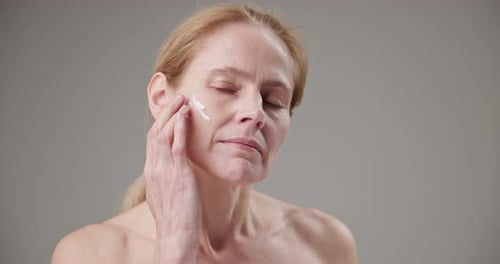 Woman applying cream to her face smiling